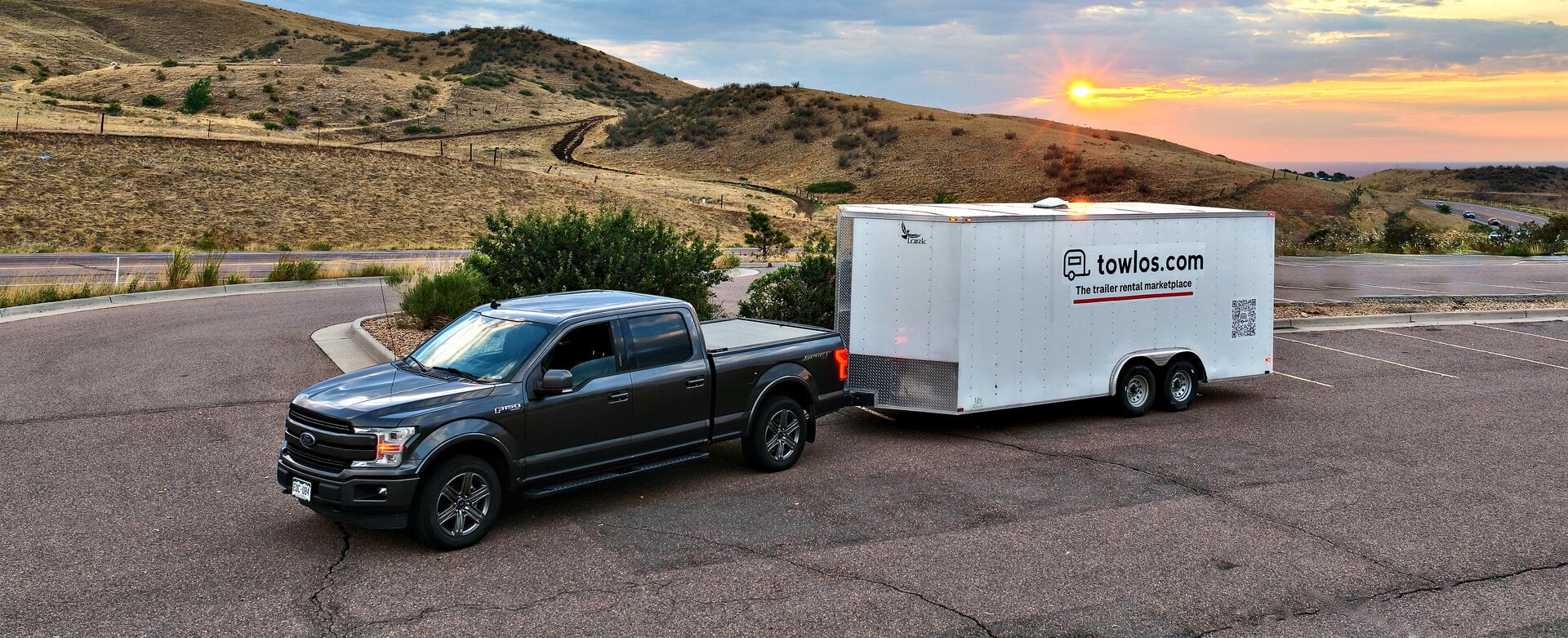 A pickup towing an enclosed towlos trailer at sunset in Colorado