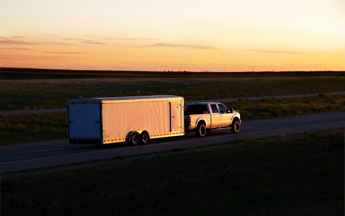 car hauler trailer driving at sunset.