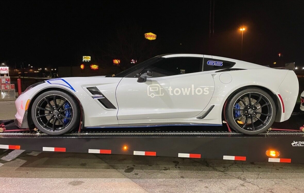towlos branded corvette on a open car hauler.
